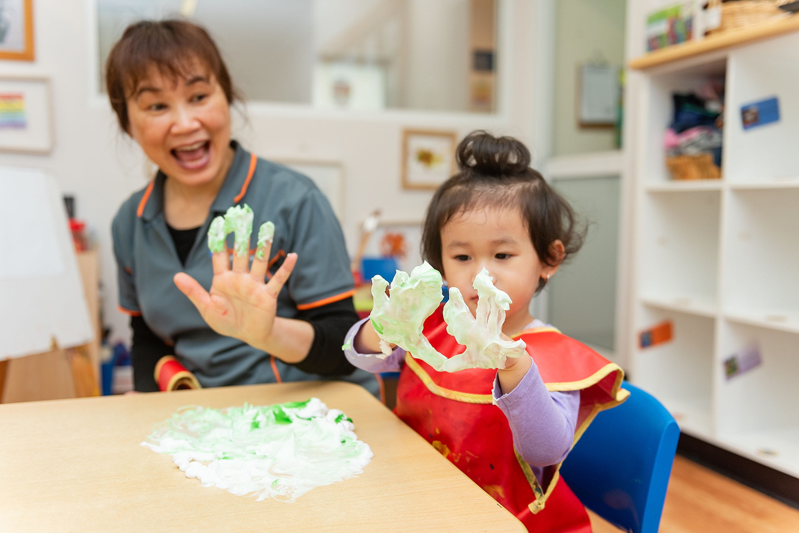 Childcare educator and child with playing with messy foam