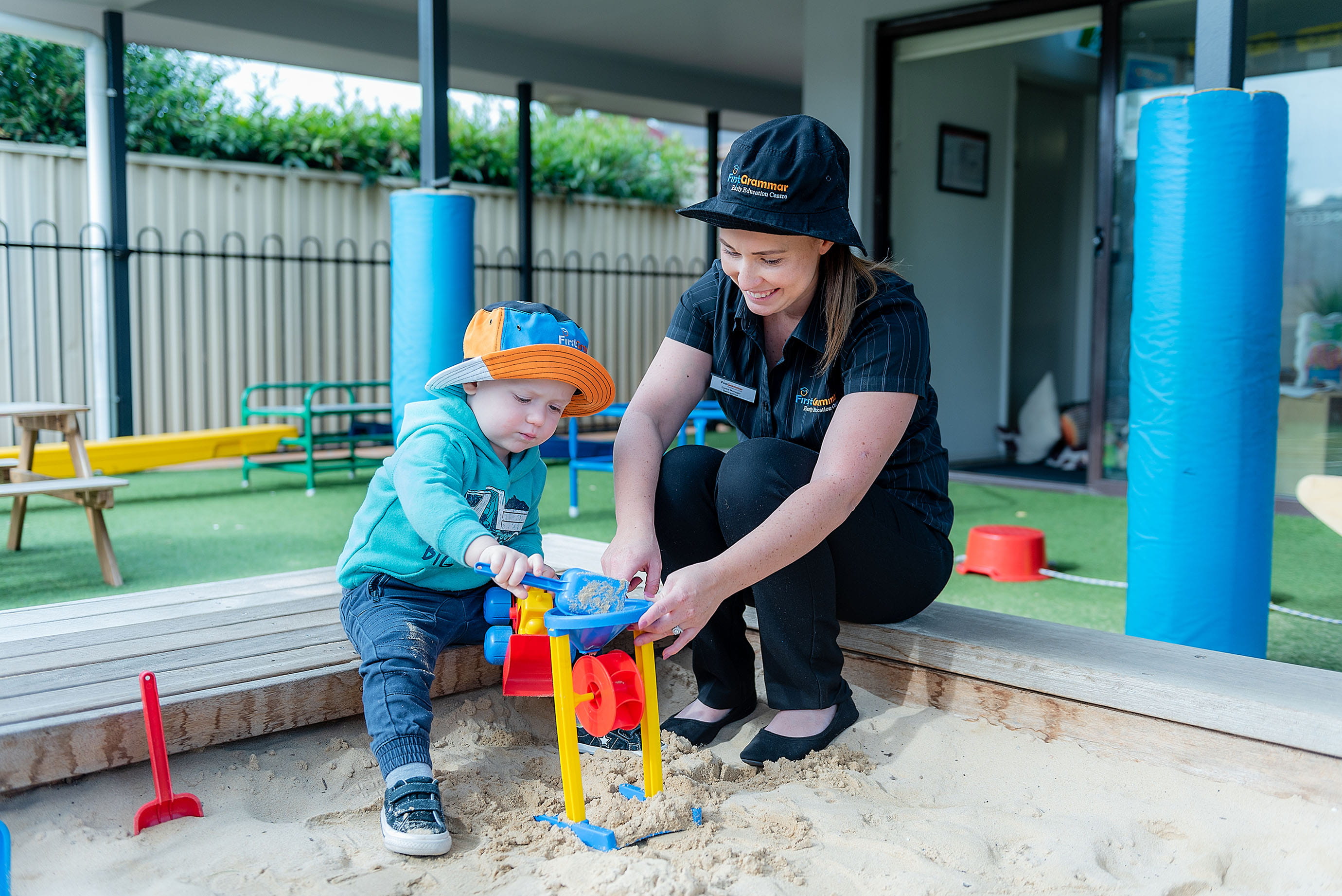 Childcare educator with boy in sandpit