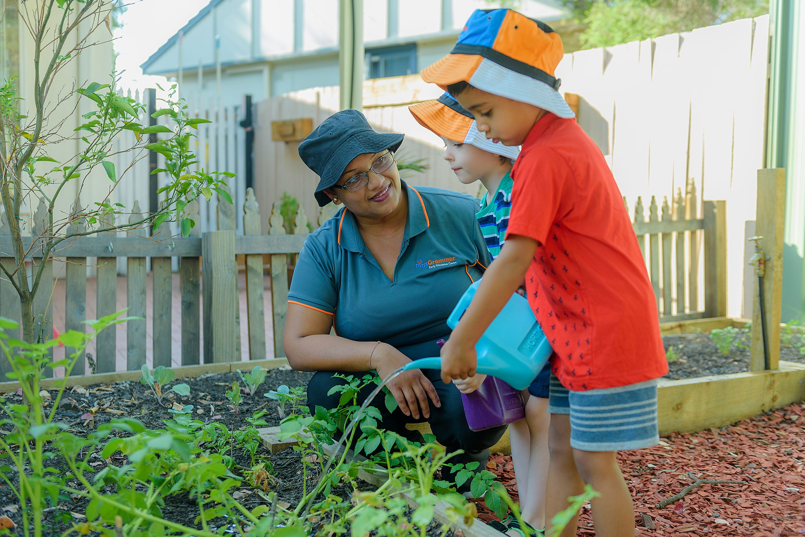 Educator watering garden with child at First Grammar Day Care