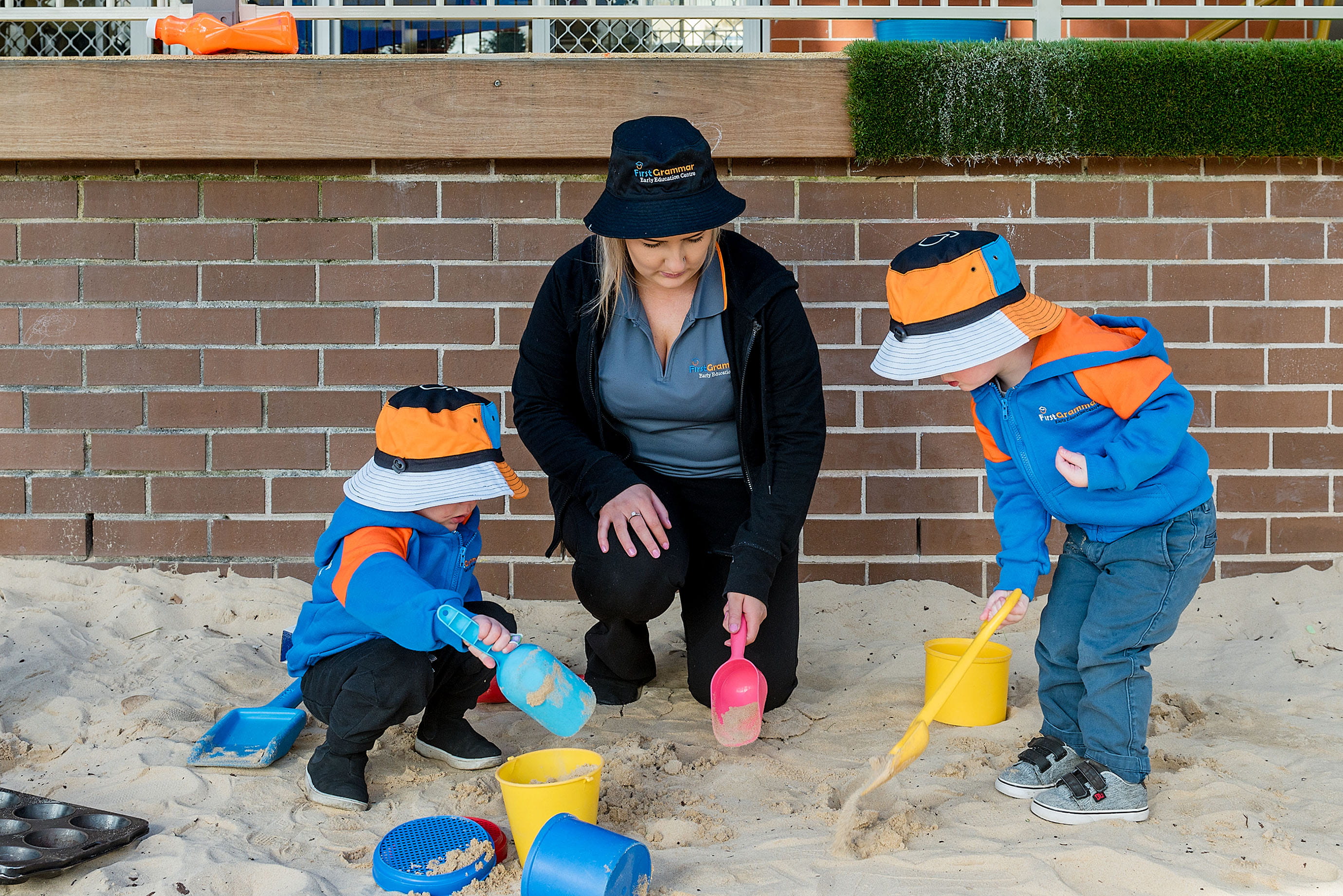 Childcare educator and children playing in the sand