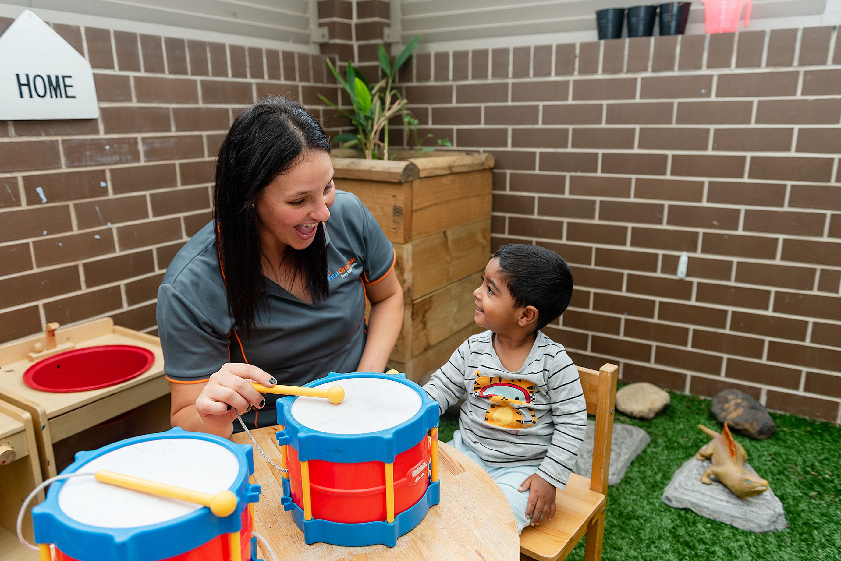 Day care educator playing drums with a child
