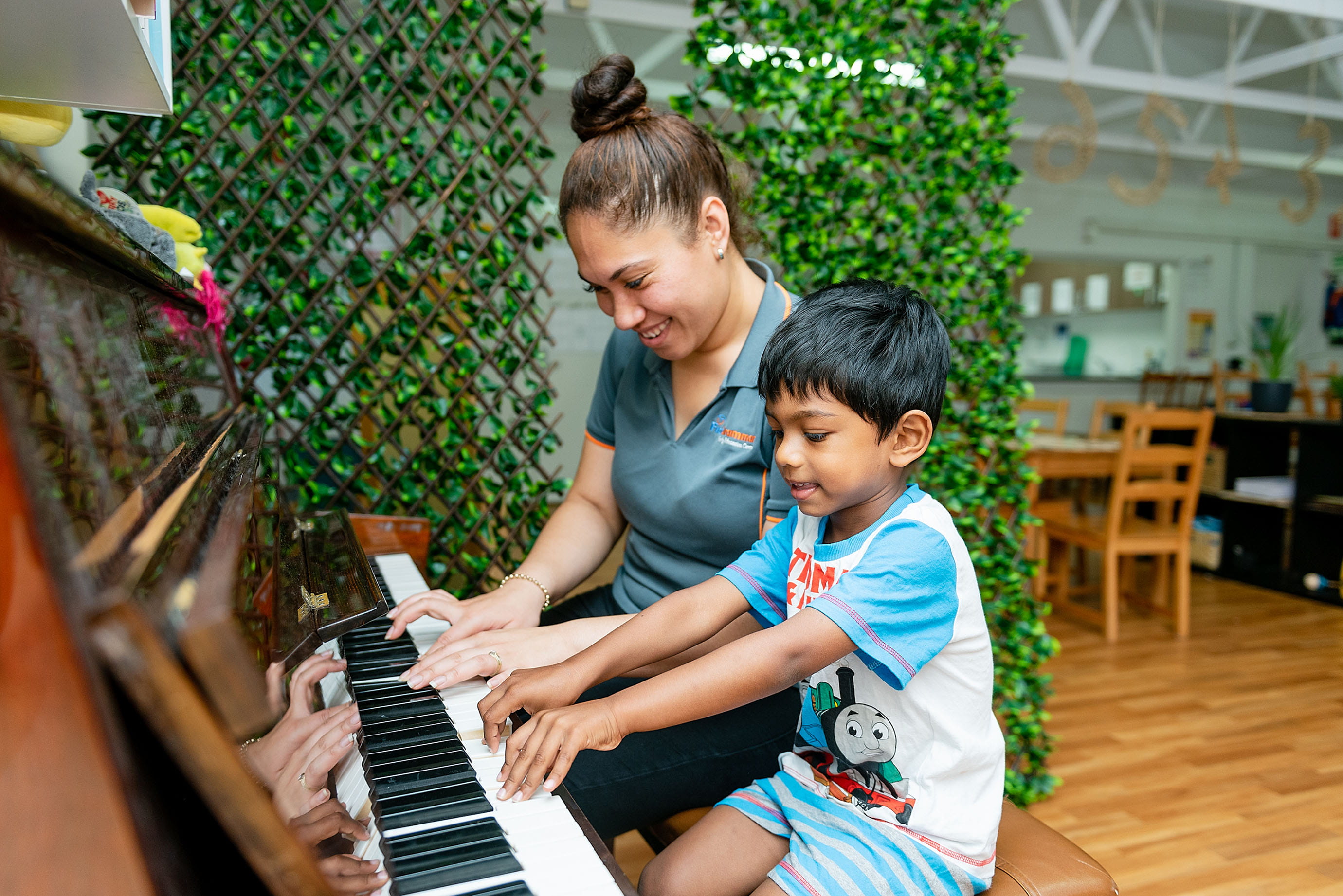 Preschool educator and child playing the piano